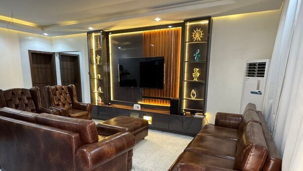 Un salon moderne avec des canapés en cuir, un téléviseur à écran plat et des panneaux muraux décoratifs.