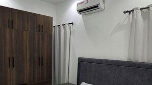 Une chambre à coucher comprenant un lit, une armoire et un appareil de climatisation.