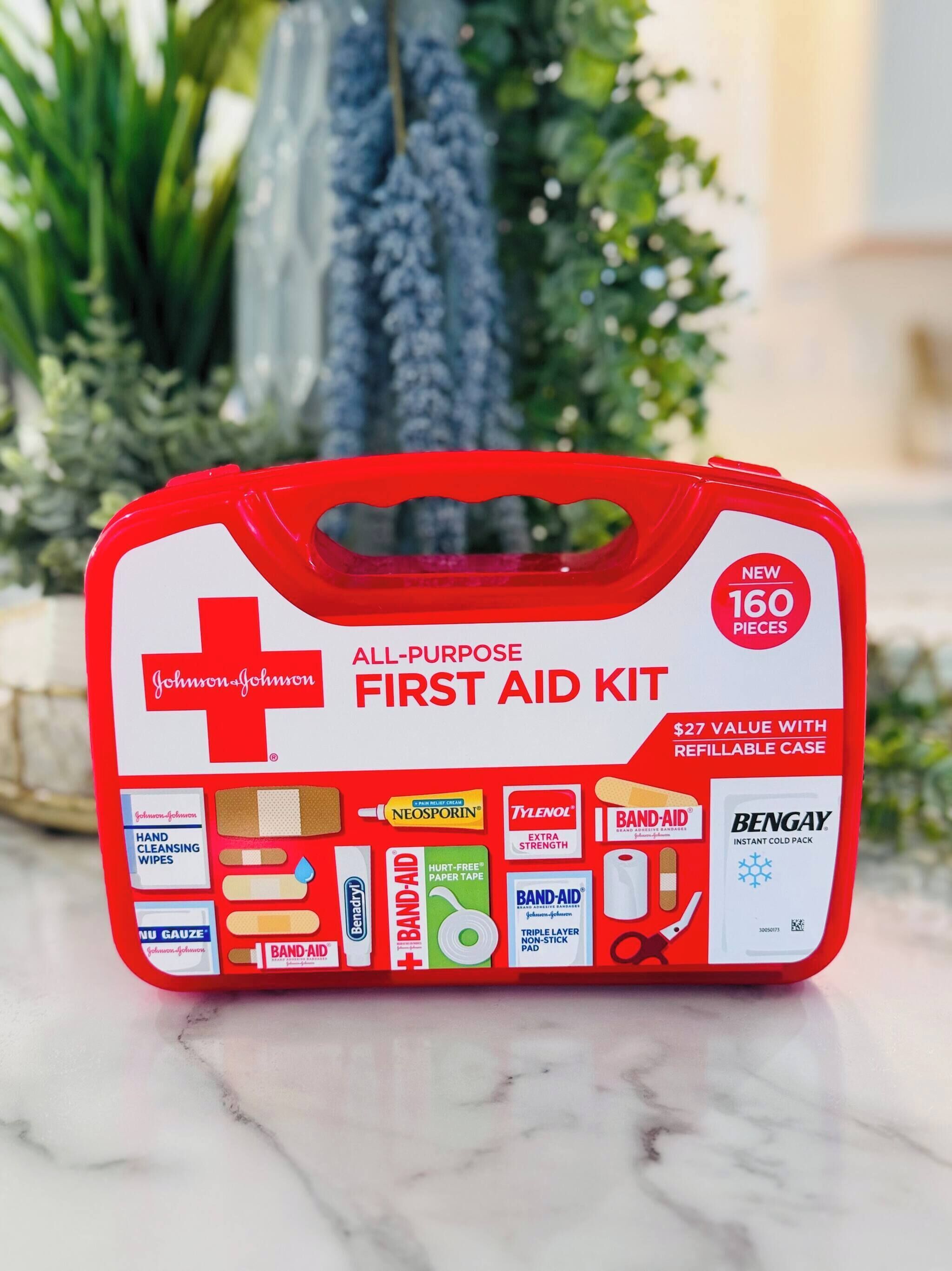 A red first aid kit with a handle, containing various medical supplies like band-aids, gauze, and wipes.