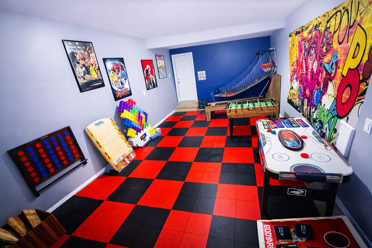 A room with a checkered floor, foosball table, and a colorful mural.