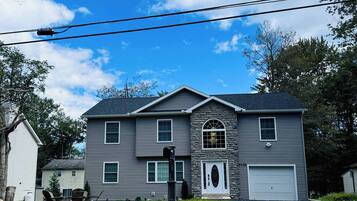A two-story house with a stone facade, a garage, and a driveway.