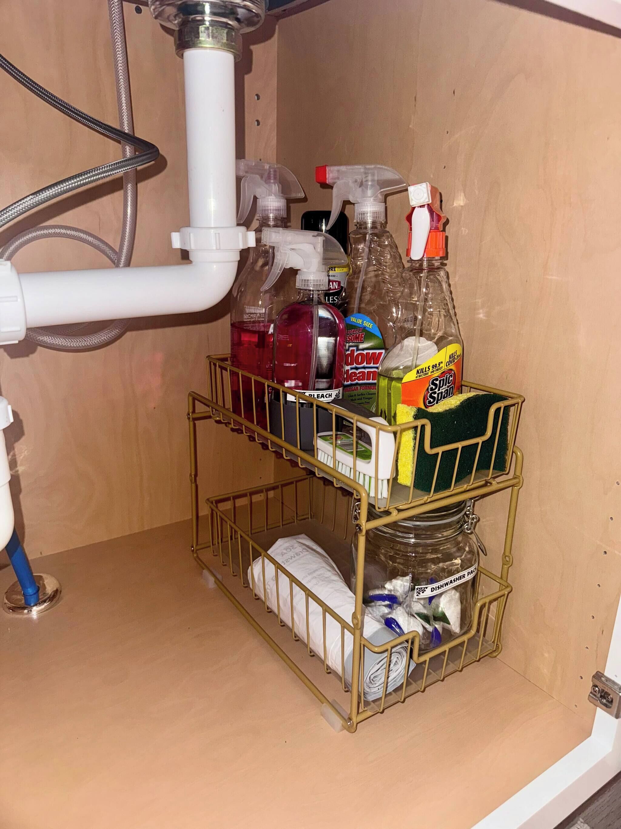 Zona de pileta de cocina con un estante metálico que contiene artículos de limpieza, lavavajillas y una botella de detergente.
