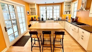 A modern kitchen with a large island, bar stools, and a view through the glass doors. - Beautiful home in Burlington's South End, humans and dogs welcome! (Burlington)