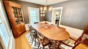 A dining room with a wooden table, chairs, a chandelier, and a cabinet. - Beautiful home in Burlington's South End, humans and dogs welcome! (Burlington)