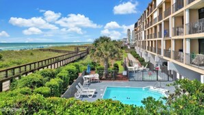 A hotel with a pool, a beach view, and a fenced garden area. - Oceanfront Comfort at the Cabana! (Carolina Beach)
