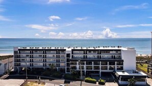 A multi-story hotel with a modern design, located near a beach with a clear view of the ocean. - Oceanfront Comfort at the Cabana! (Carolina Beach)