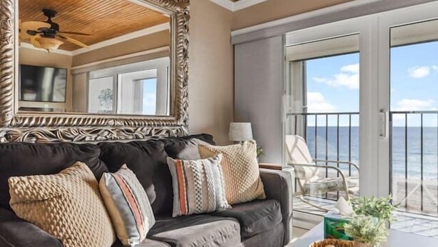 A living room with a dark gray sofa, a large mirror, and a coffee table with a basket and books. - Oceanfront Comfort at the Cabana! (Carolina Beach)
