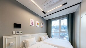 Una camera d'albergo con due letti, una TV e una finestra vista città.