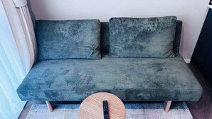Un sofá con un control remoto sobre una mesa redonda de madera.