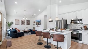 A modern kitchen with white cabinets, stainless steel appliances, and a central island. - Pelican Landing At The Bay (Pensacola)