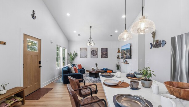 A spacious living area with a dining table, chairs, and a kitchen area with modern appliances. - Pelican Landing At The Bay (Pensacola)