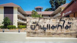 Un edificio con un letrero en un alfabeto extranjero, un corredor cubierto y una pared de ladrillo con texto.
