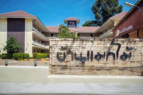 A building with a sign in a foreign script, a covered walkway, and a brick wall with text.