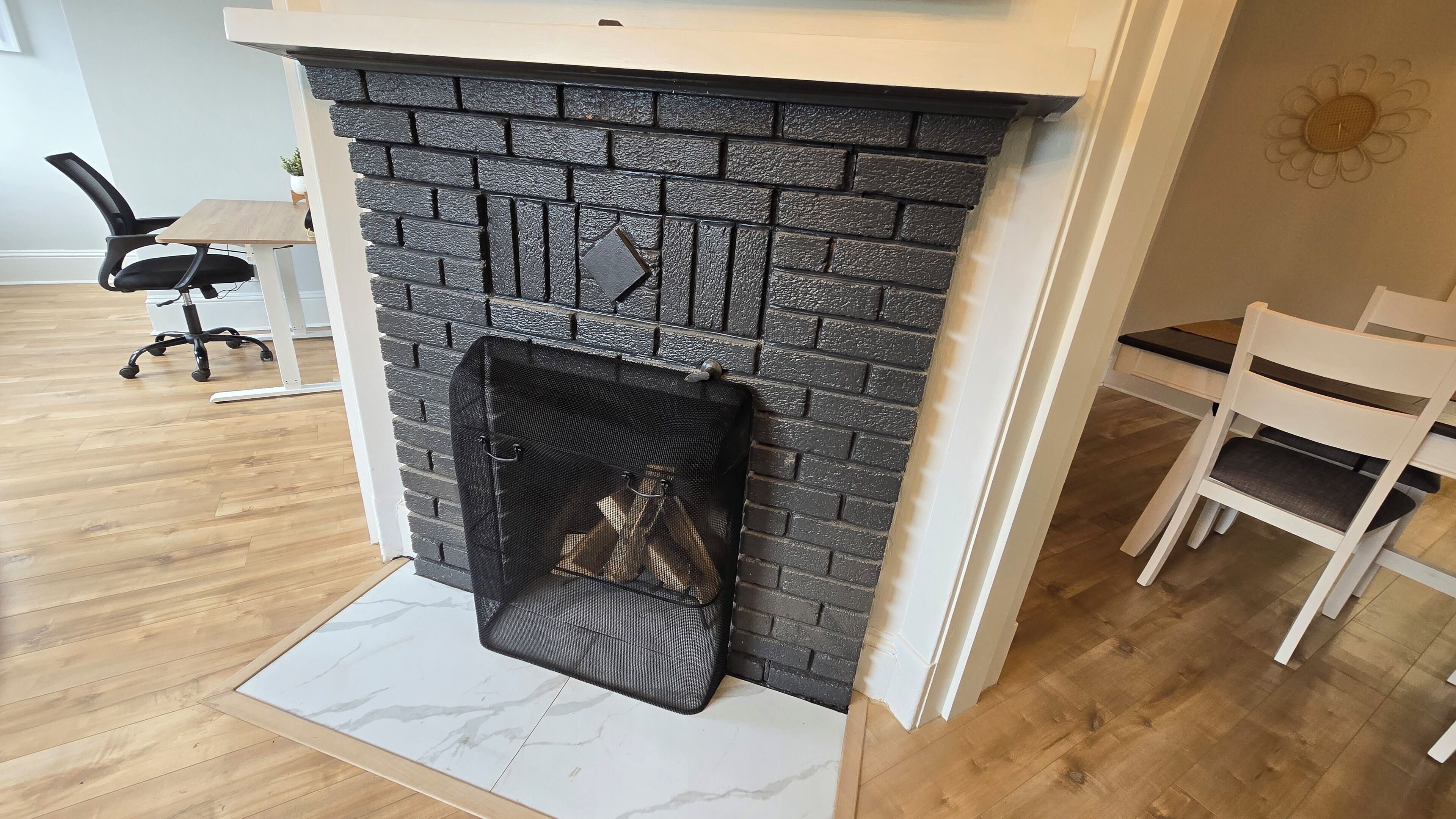 Una sala de estar moderna con una chimenea de ladrillo, una repisa blanca y una alfombra con diseño de mármol.
