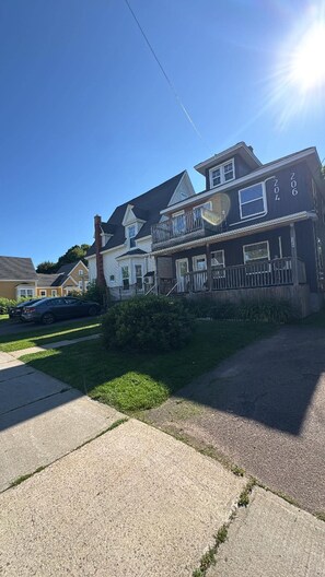 Ein Wohnhaus mit zweistöckiger Struktur, einer sichtbaren Veranda und einer Auffahrt zu einem parkenden Auto.