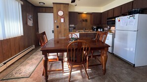 Eine Küche mit Holzschränken, einem weißen Kühlschrank, einem Esstisch mit Stühlen und einem Deckenventilator.