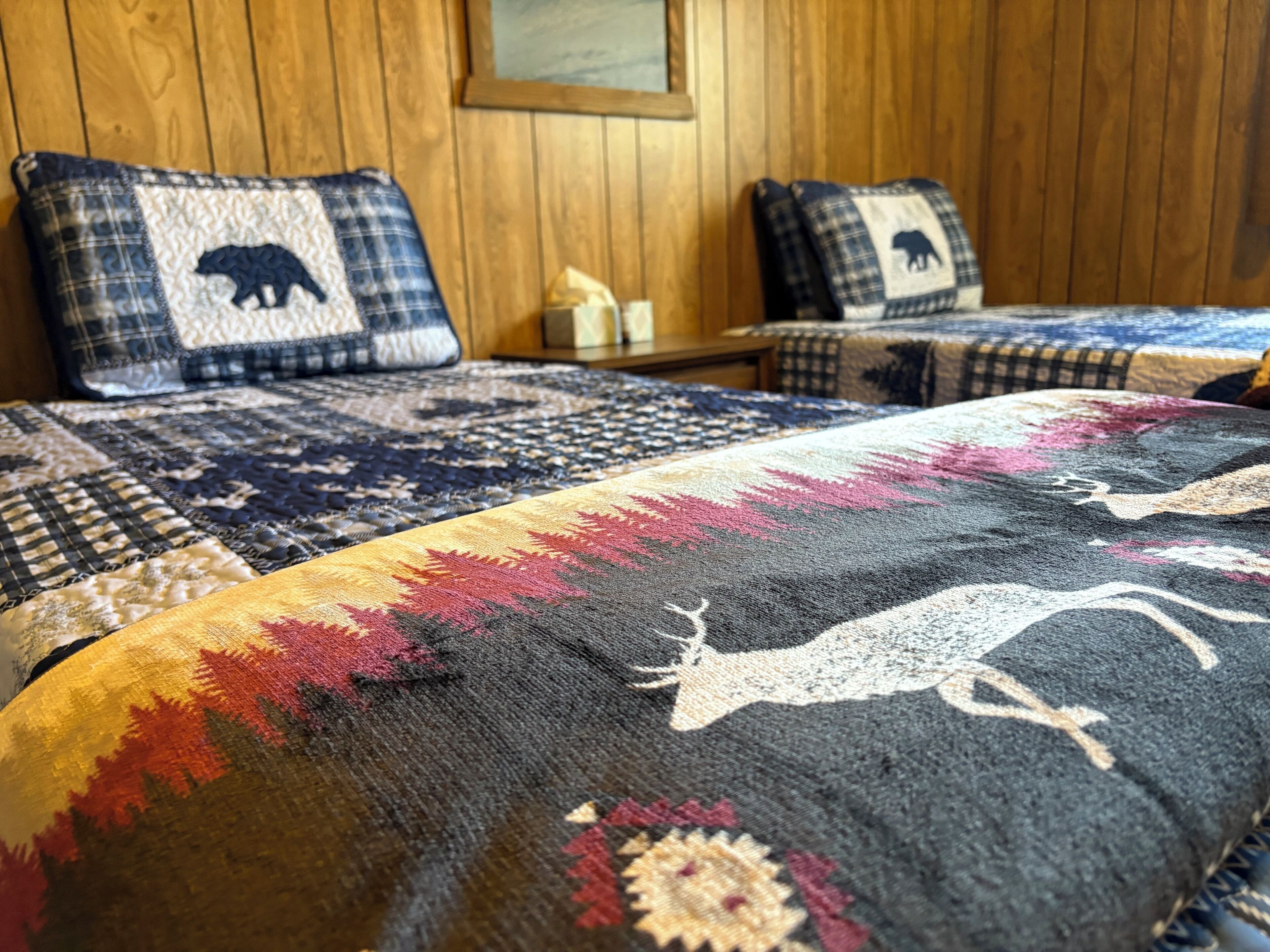 A bed with a patterned blanket and two pillows with animal designs.