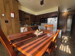 Une cuisine moderne avec des meubles en bois, un réfrigérateur en acier inoxydable et une table à manger avec des chaises.