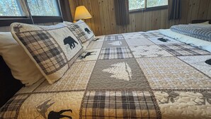 Ein Schlafzimmer mit einem großen Bett, einem Fenster mit Vorhängen und einer Holzwand.