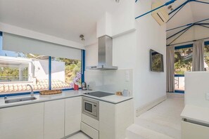 Eine moderne Küche mit Backofen, Spüle und Fenster mit Blick auf einen Garten.