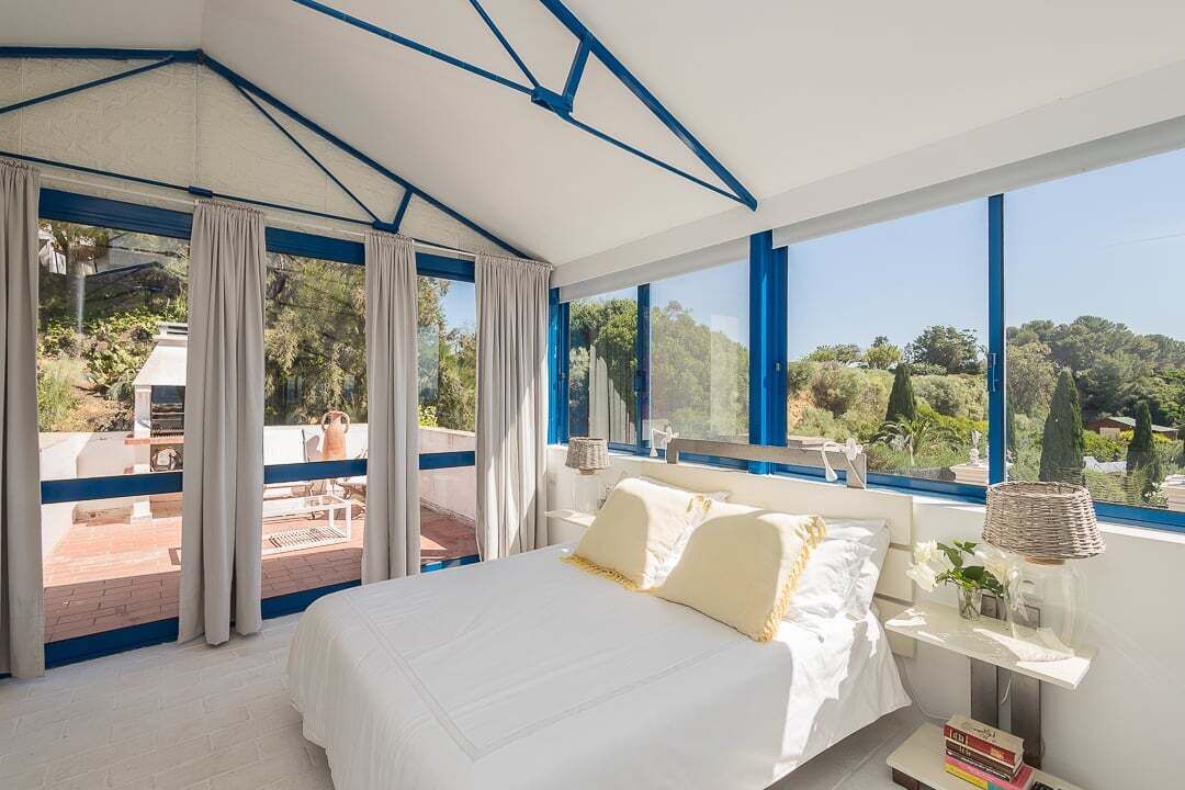Un dormitorio con una cama grande, vistas al exterior y un balcón.