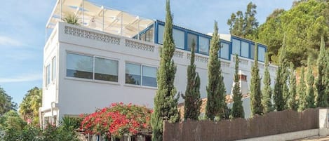 Ein modernes, zweistöckiges Gebäude mit großen Fenstern, einer flachen Dachkonstruktion und einem Balkon.