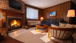 Una sala de estar con chimenea, un sofá, una mesa de centro y un sillón mecedora.