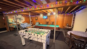 Una habitación con mesa de fútbol, mesa de billar y dardos.