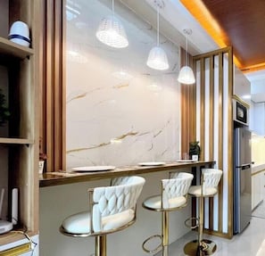 A modern kitchen with a marble backsplash, pendant lights, and bar stools. - Room-modern Style 2-br in Smdc (Iloilo)