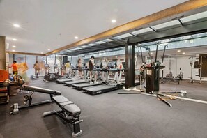 A gym with treadmills, weight machines, and a bench. - 2-Bed High-Rise Apartment with Pool & Gym (Melbourne)