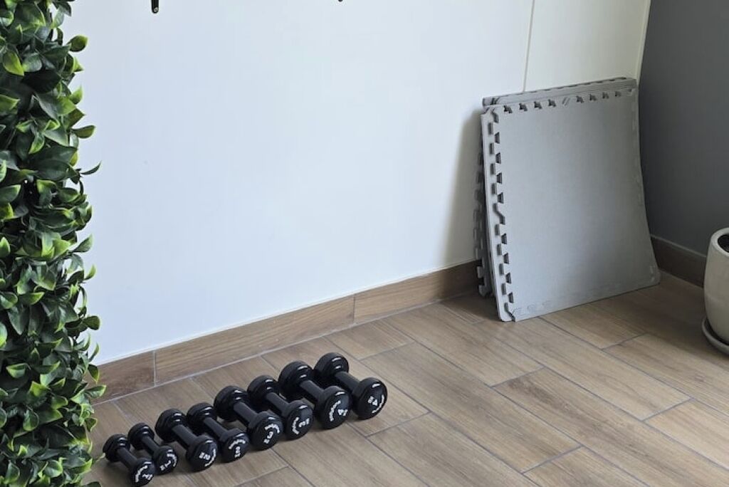 Een kamer met een houten vloer, een radiator en een plant.