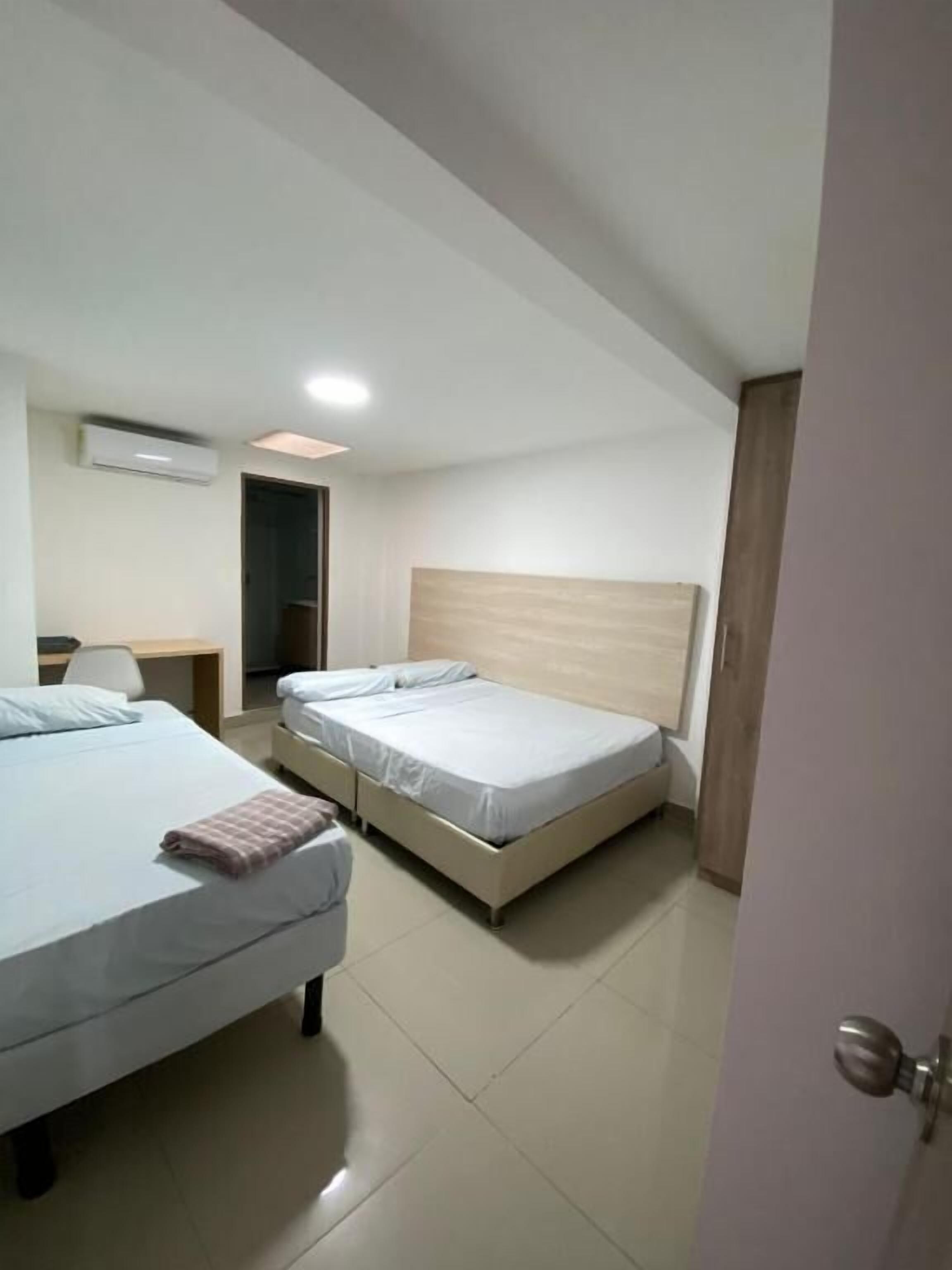 Una camera d'albergo con due letti, una scrivania e un condizionatore.