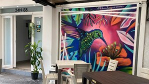 An outdoor seating area with a mural, a potted plant, and a table and chairs. - Hotel Pasarela Real Cail (Cali)
