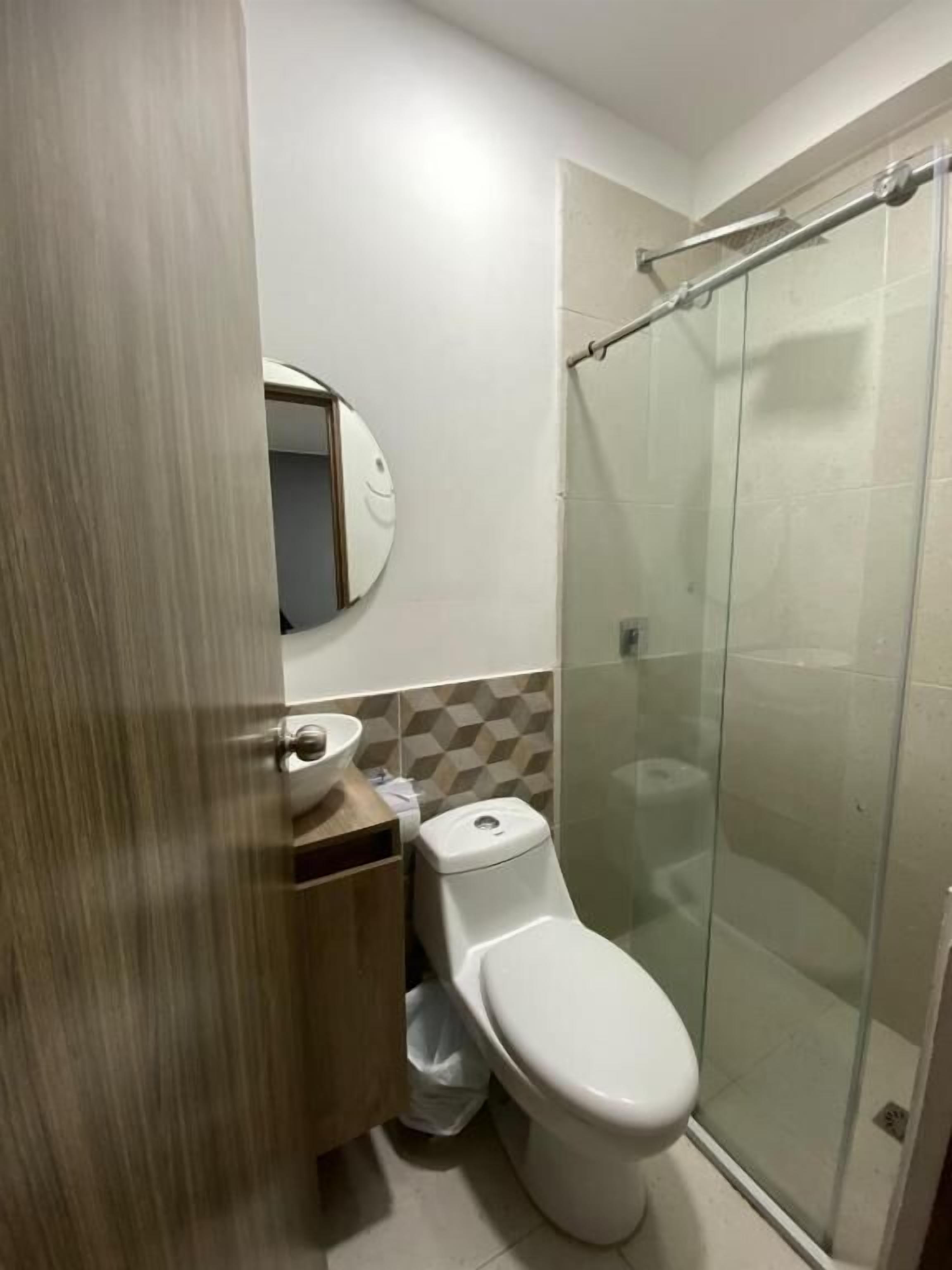 Une salle de bain comprenant des toilettes, un lavabo, un miroir et une douche à parois de verre.
