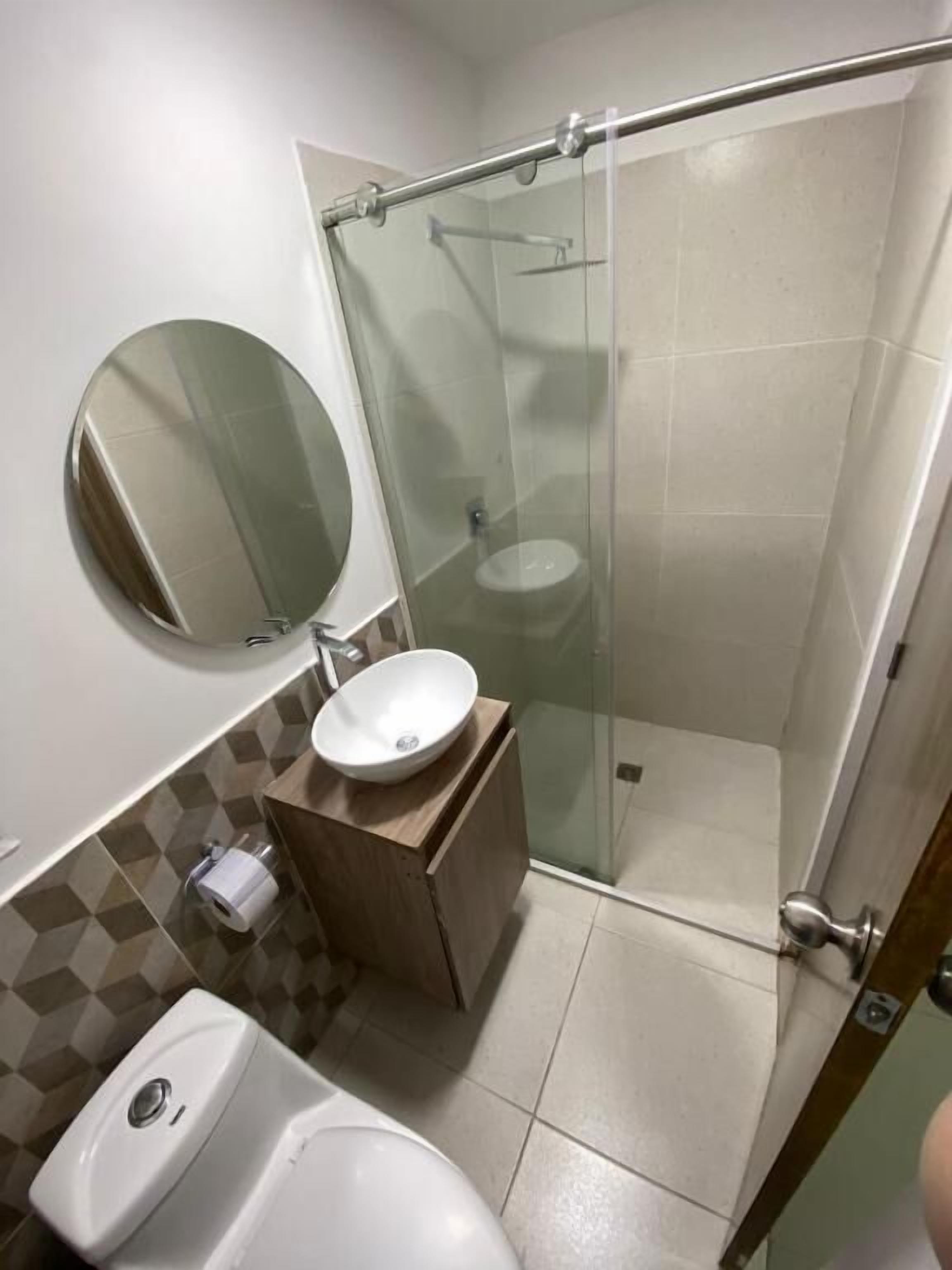 Une salle de bain comprenant des toilettes, un lavabo avec un miroir et une cabine de douche en verre.