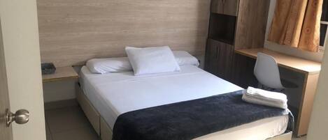 A bedroom with a bed, a desk, and a chair.