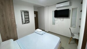 A hotel room with a bed, a TV, a chair, and an air conditioning unit. - Hotel Pasarela Real Cail (Cali)