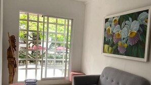 A modern living room with a grey sofa, a glass coffee table, and a wooden sculpture. - Hotel Pasarela Real Cail (Cali)