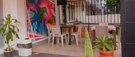 A patio area with a table and chairs, potted plants, and a colorful mural on the wall.
