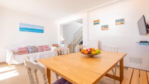 Ein modernes Wohnzimmer mit einem Holzespeise Tisch, einem weißen Sofa und einer Obstschale.