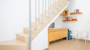 Eine Treppe mit Metallgeländer, einem Holzkabinett und zwei weißen Stühlen.