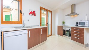 A modern kitchen with wooden cabinets, a dishwasher, an oven, and a microwave. - RESIDENCIAL SUITES VALLDEMOSSA - S'Arxiduc (Valldemossa)