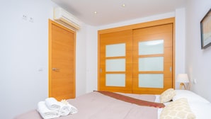 A hotel room with a bed, two doors, a wall-mounted air conditioner, and a lamp. - RESIDENCIAL SUITES VALLDEMOSSA - S'Arxiduc (Valldemossa)
