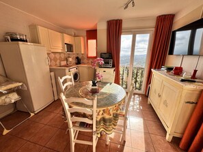 Eine kompakte Küche mit Essbereich, einer Waschmaschine und einem Balkon mit Blick.