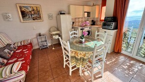 Un espacio habitable compacto con comedor, kitchenette y sofá.