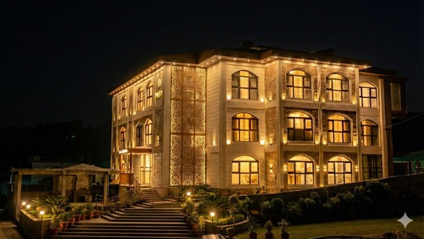 A multi-story building with a symmetrical facade, large windows, and a central entrance with steps. - Suryoday The Vaikunth (Badrinath)