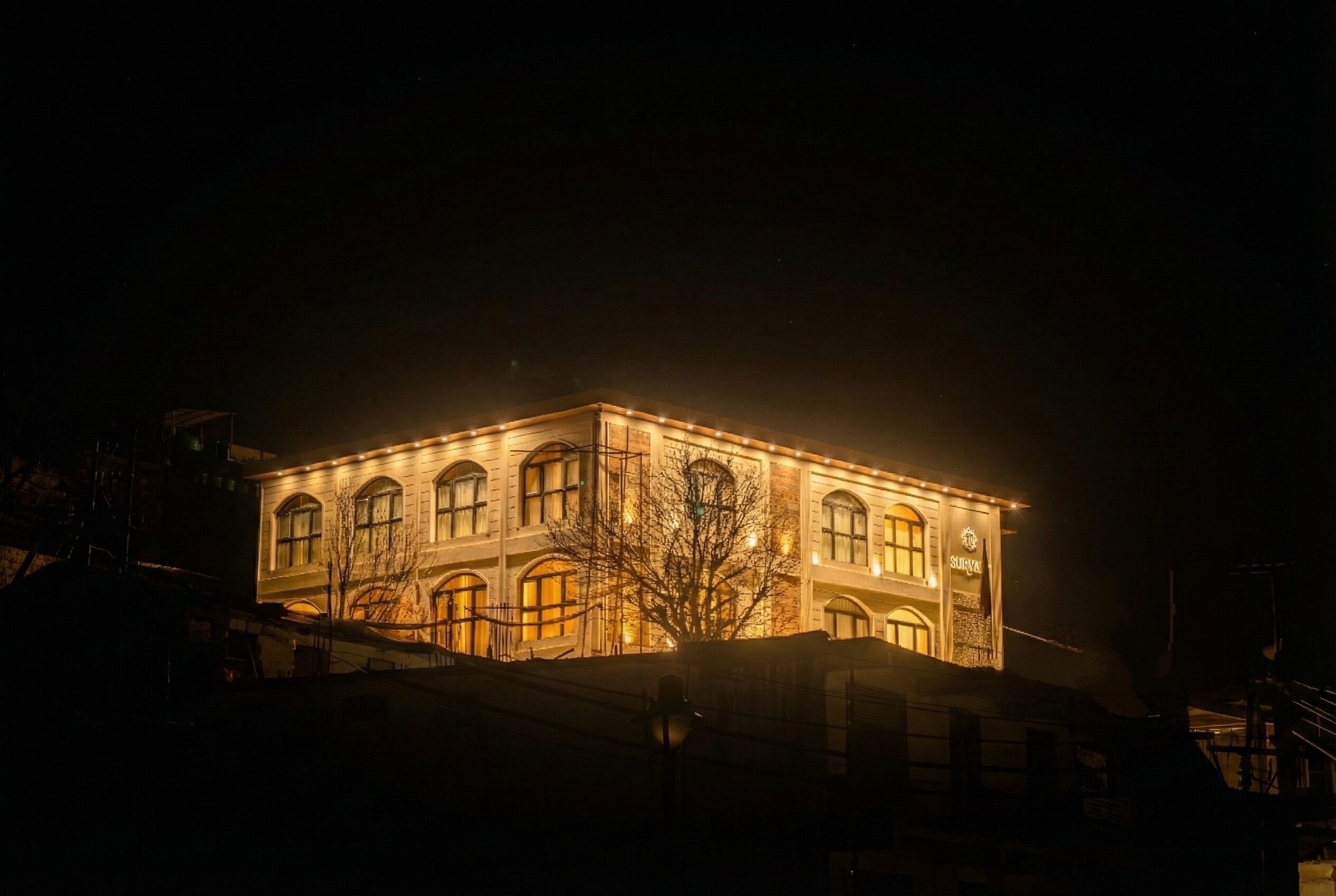 Un edificio de varios pisos con ventanas iluminadas y un letrero que dice "SCHOOL OF ART".