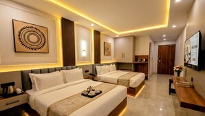 A modern hotel room with two beds, a wooden headboard, a bedside table with a coffee maker, and a TV on the wall. - Suryoday The Vaikunth (Badrinath)