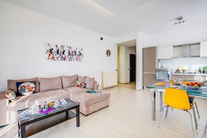 A modern living room with a sofa, a coffee table, and a dining area with a chair and table. - Asia Apartment: 2BR in Laveno Center (Laveno Mombello)