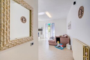 Ett modernt vardagsrum med en stor spegel, en rosa soffa och en gunghest.